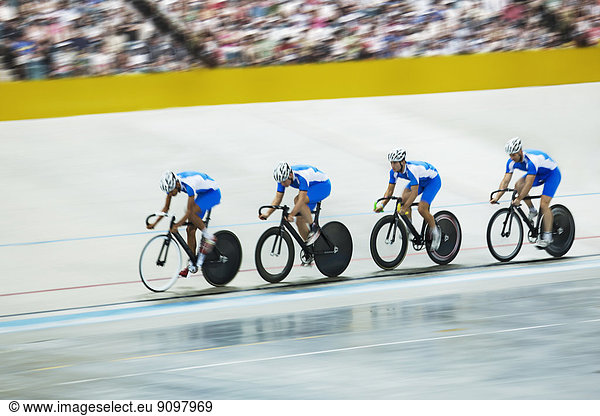 Track cycling team riding around velodrome