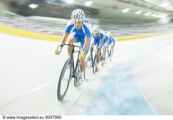 Track cycling team riding around velodrome