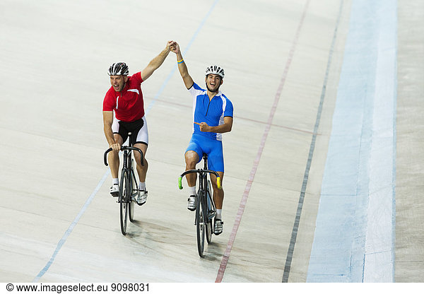 Track cyclists celebrating in velodrome