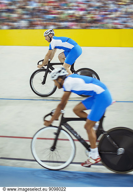 Track cyclists riding in velodrome