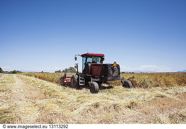 Tractor on agricultural field against blue sky