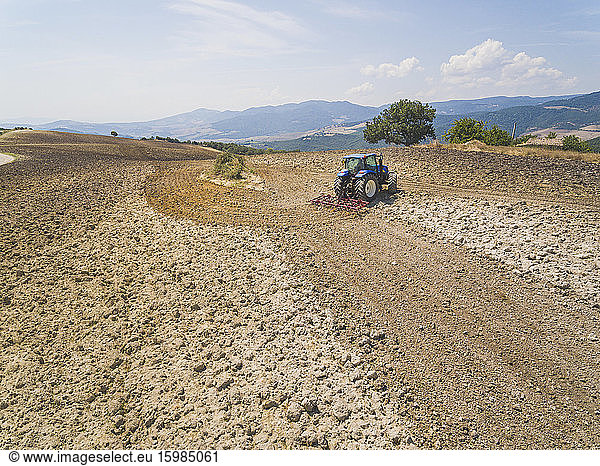 Tractor plowing in farm against sky at Basilicata  Italy
