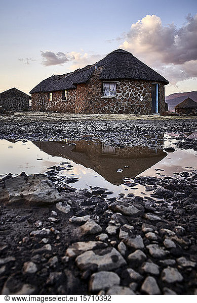 Traditional stone houses and reflection in a puddle  Lesotho