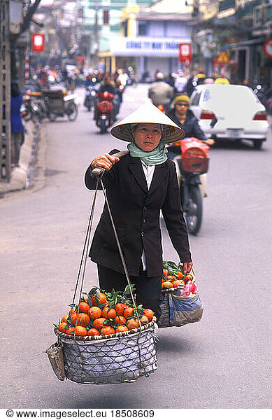 Traditional Woman Vendor in Straw Hat Carrying Oranges Over Shoulder Hanoi Vietnam