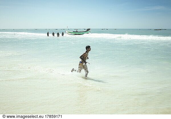Traditioneller Fischereistrand  Plage des Pêcheurs Traditionnels  Ankunft der Fischerboote  ein Junge sammelt einzelne Fischer  die ins Wasser fallen  Nouakchott  Mauretanien  Afrika
