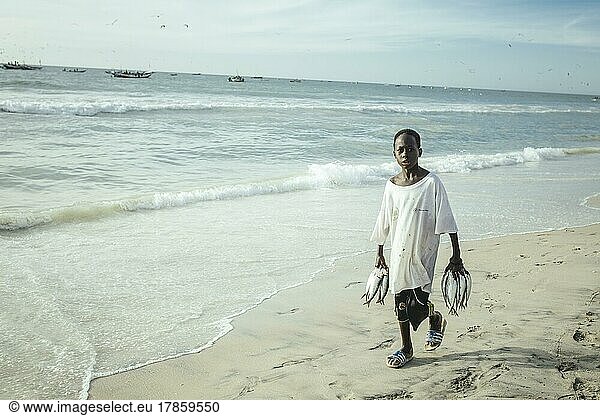 Traditioneller Fischereistrand  Plage des Pêcheurs Traditionnels  Ankunft der Fischerboote  ein Junge sammelt einzelne Fischer  die ins Wasser fallen  Nouakchott  Mauretanien  Afrika