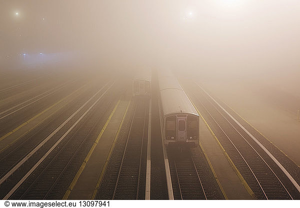 Train on illuminated railroad tracks at dusk in foggy weather