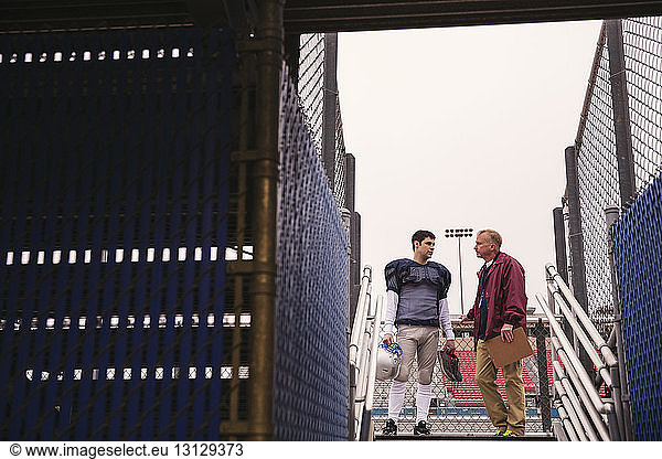 Trainer diskutiert mit American-Football-Spieler im Stadion durch den Eingang gesehen