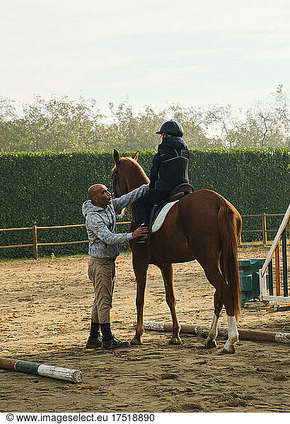 Trainer teaching kid horseback riding with obstacles.