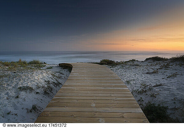 Tranquil sunset scene with a walkway over the beach dunes