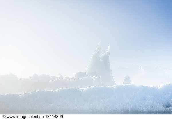 Tranquil view of icebergs against sky during foggy weather