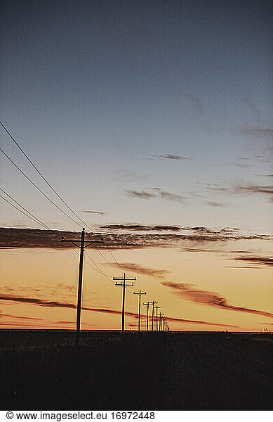 transmission lines recede into distance at sunrise prairies of Kansas