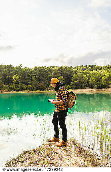 Traveler reading guide while exploring beautiful lake doing tourism