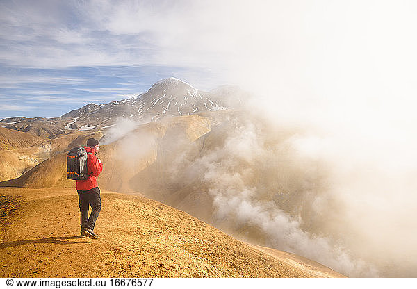 Traveling man in mountainous terrain with clouds