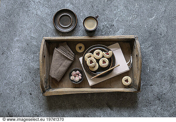 Tray with jam cookies  note pad  dish cloth  flower heads and cup of coffee