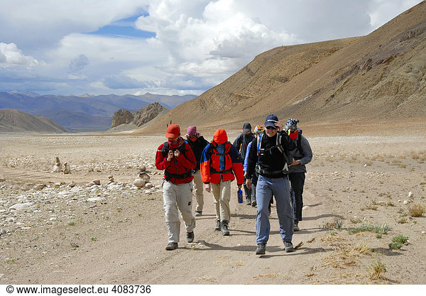 Trekkinggruppe geht über ein weites ebenes Flußtal in starkem Sturm bei Lungchang Tibet China