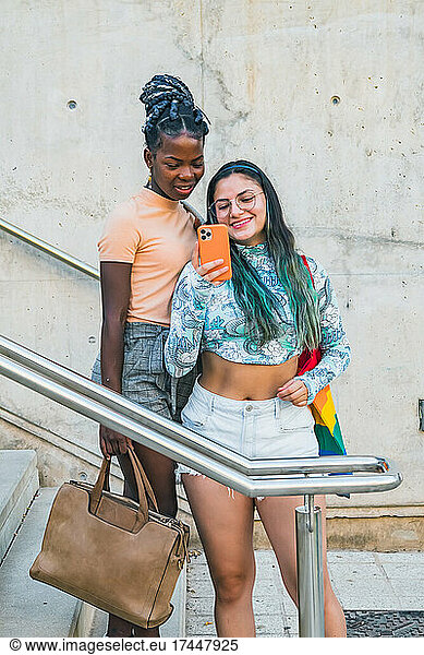 Trendy multiethnic lesbian girlfriends taking selfie on smartphone