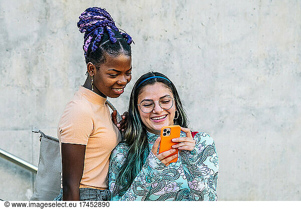 Trendy multiethnic lesbian girlfriends taking selfie on smartphone