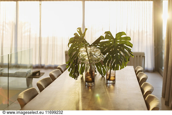 Tropical plant leaves in vases on dining table