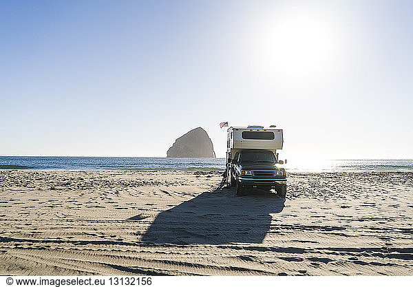 Truck camper at beach against clear sky on sunny day