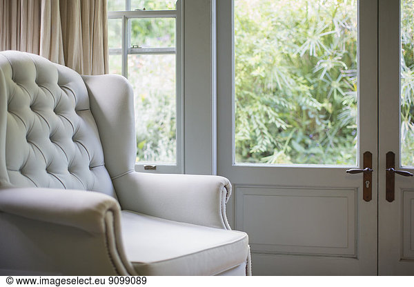 Tufted wingback chair near window