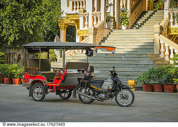 Tuk tuk taxi on street outside grand staircase to hotel or resort.