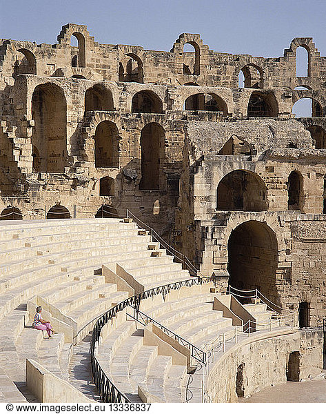 TUNISIA El Djem Roman Amphitheatre interior with a lone woman sitting on terraces