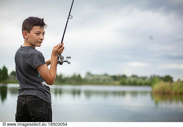 Tween boy casting fishing line at a pond