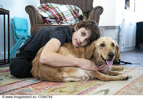 Tween boy hugging Golden Retriever.