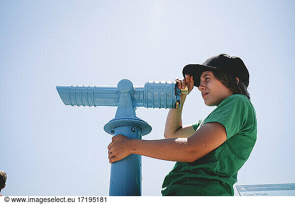 Tween Boy Peeks Through Spyglass on a Blue Sky Day