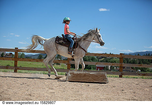 Tween cantering on horse in outdoor arena
