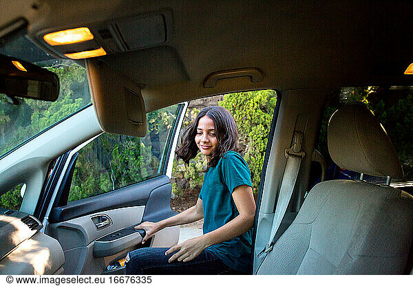 Tween girl enters the car to sit in the front seat