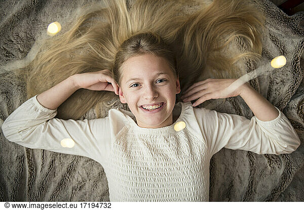 Tween Girl Lying on Blanket Surrounded by Christmas Holiday Lights