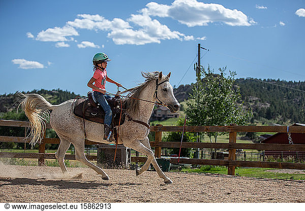 Tween girl riding horse in outdoor arena