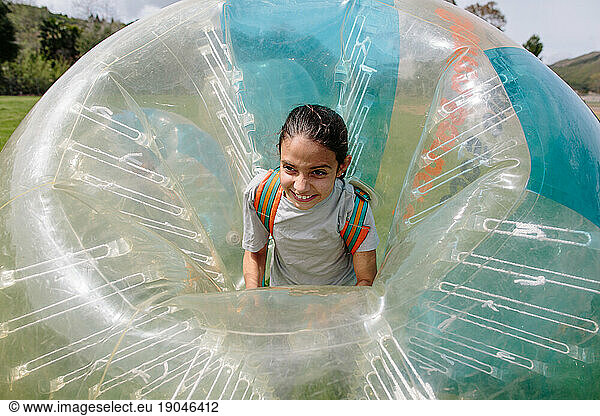 Tween girl smiles big with excitement while wearing an inflatable ball