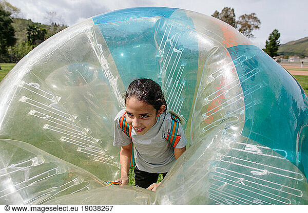 Tween girl smiles while inside a bubble soccer bubble suit