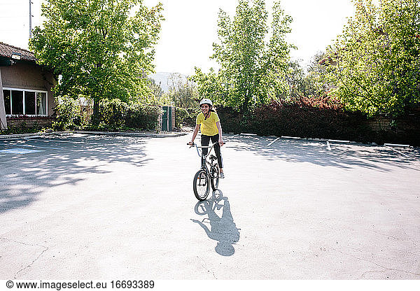 Tween girl stands on the pedals of her bike while smiling