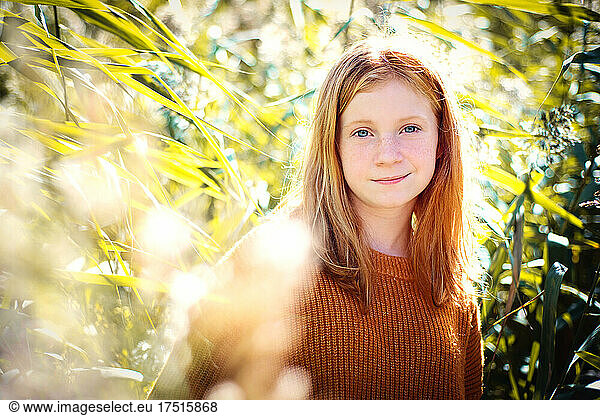 Tween girl with red hair outdoors tall grass.