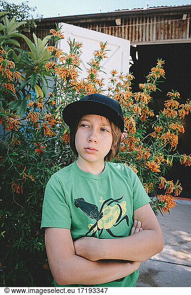 Tween in a graphic tee and hat contemplates life