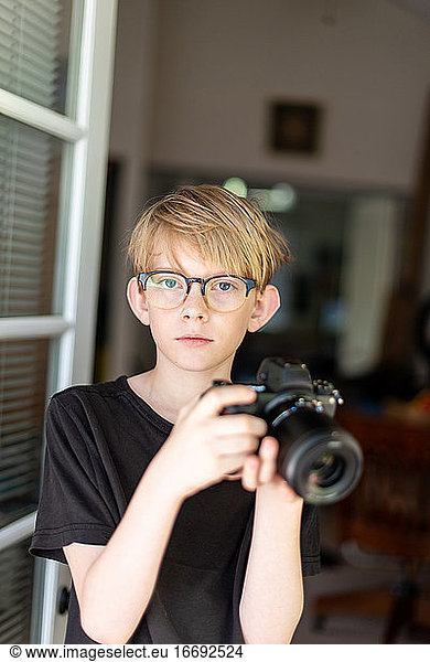 Tween nimmt Blickkontakt auf und hält eine moderne Kamera in der Tür zum Haus