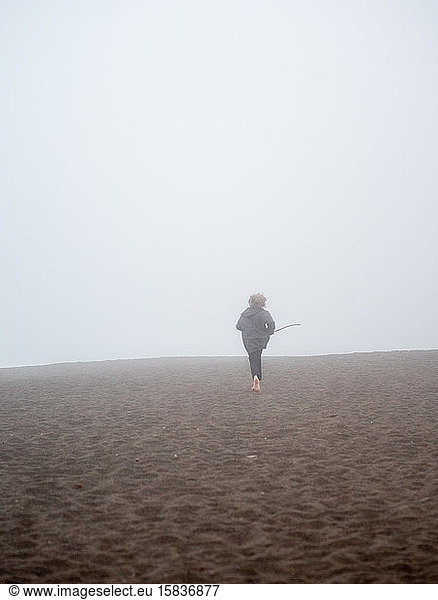 Tween running away across beach through fog