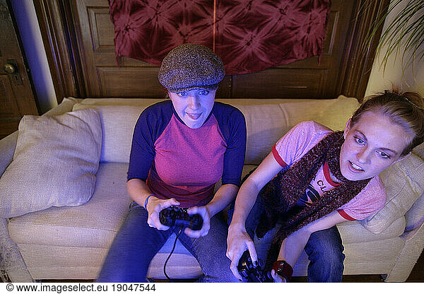 Twenty-year-old women play video games in their apartment.