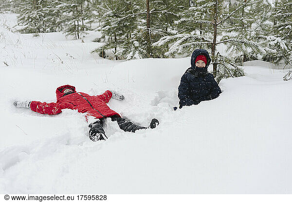 Twin brothers playing on snow in forest