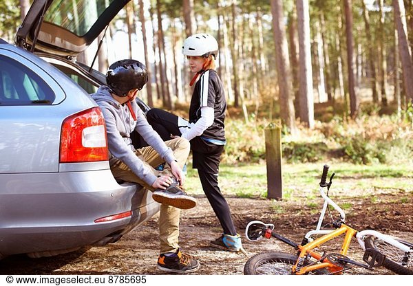 Twin brothers preparing to ride BMX bikes in forest