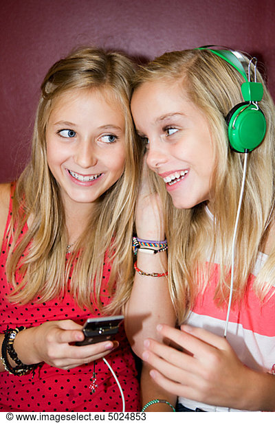 Twin girls listening to music from mp3 player
