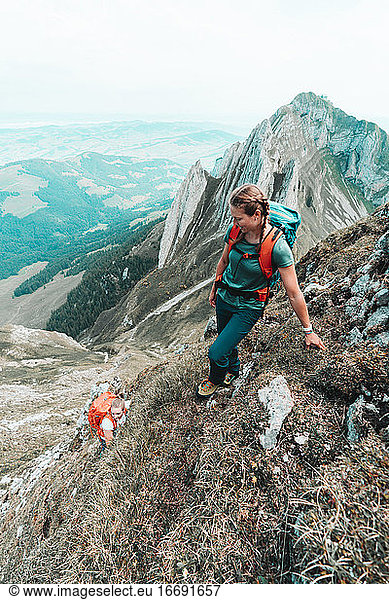Two active female climbers ascending steep grass mountain in CH