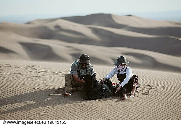 two adventurers take shelter from the whipping wind of the sand dunes