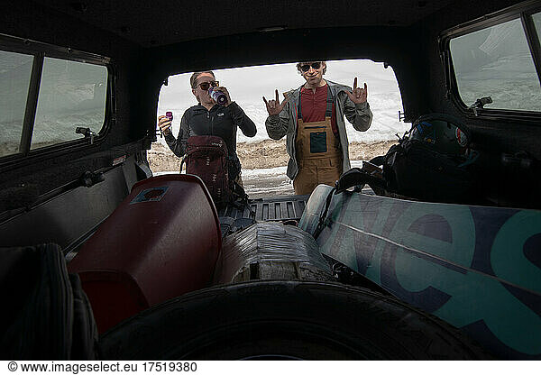 Two backcountry snowboarders pulling gear from a truck