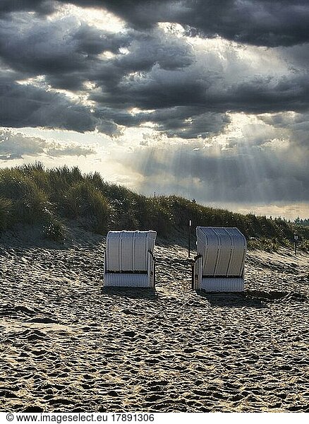 Two beach chairs in front of a dune in autumn  sun rays through cloud cover  backlight  Utersum  Föhr Island  North Frisia  North Sea  Schleswig-Holstein  Germany  Europe