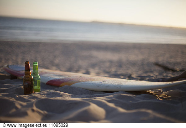Two beer bottles with surfboard on the beach during sunset  Viana do Castelo  Norte Region  Portugal